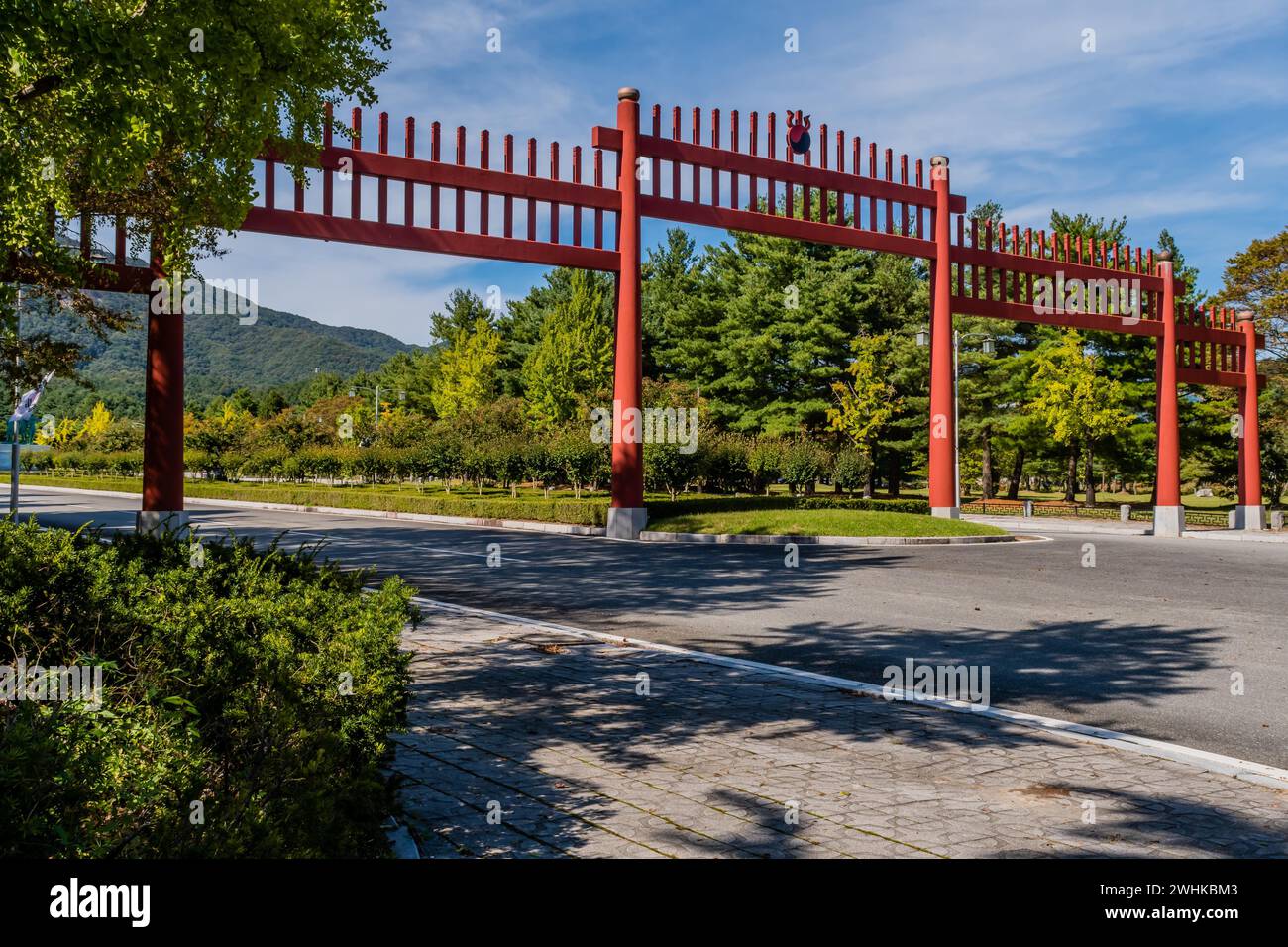 Large red wooden gate across four lane road in public park in South Korea Stock Photo
