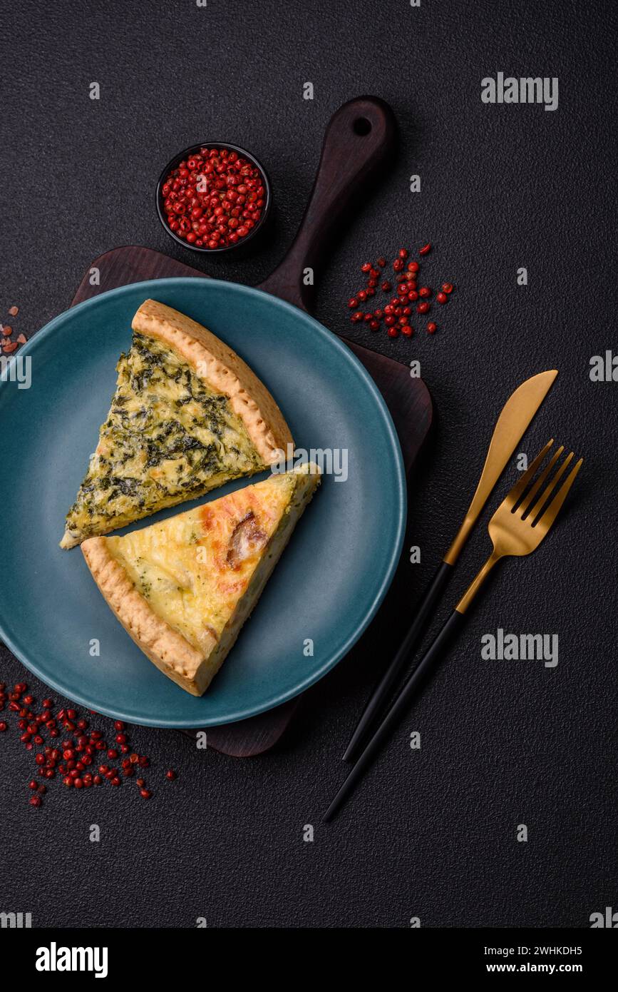 Delicious crispy quiche cut into slices with cheese, broccoli, tomatoes, salt, spices and herbs on a dark concrete background Stock Photo