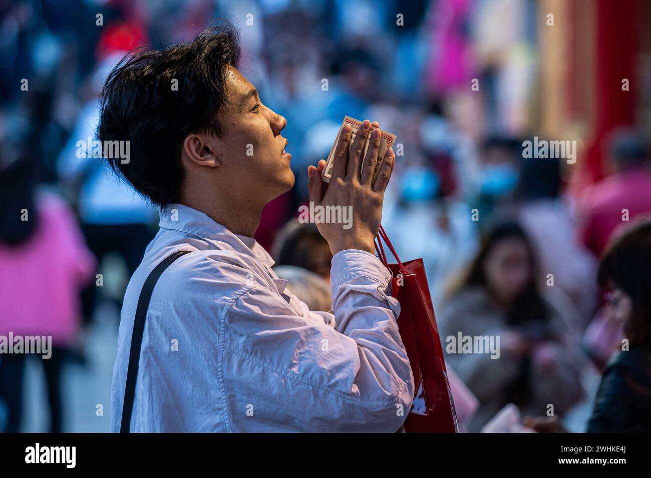 A worshipper starts the Year of the Dragon by offering prayers at the Wong Tai Sin Temple. The Sik Sik Yuen Wong Tai Sin Temple is one of the largest Taoist temples in Hong Kong and many people come here to offer the first joss sticks of the new year along with prayers for happiness and health. Stock Photo