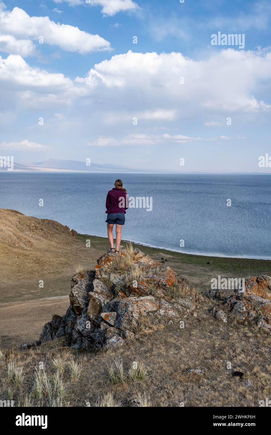 Tourist standing on a hill, view of mountain lake Song Kul, Naryn region, Kyrgyzstan Stock Photo