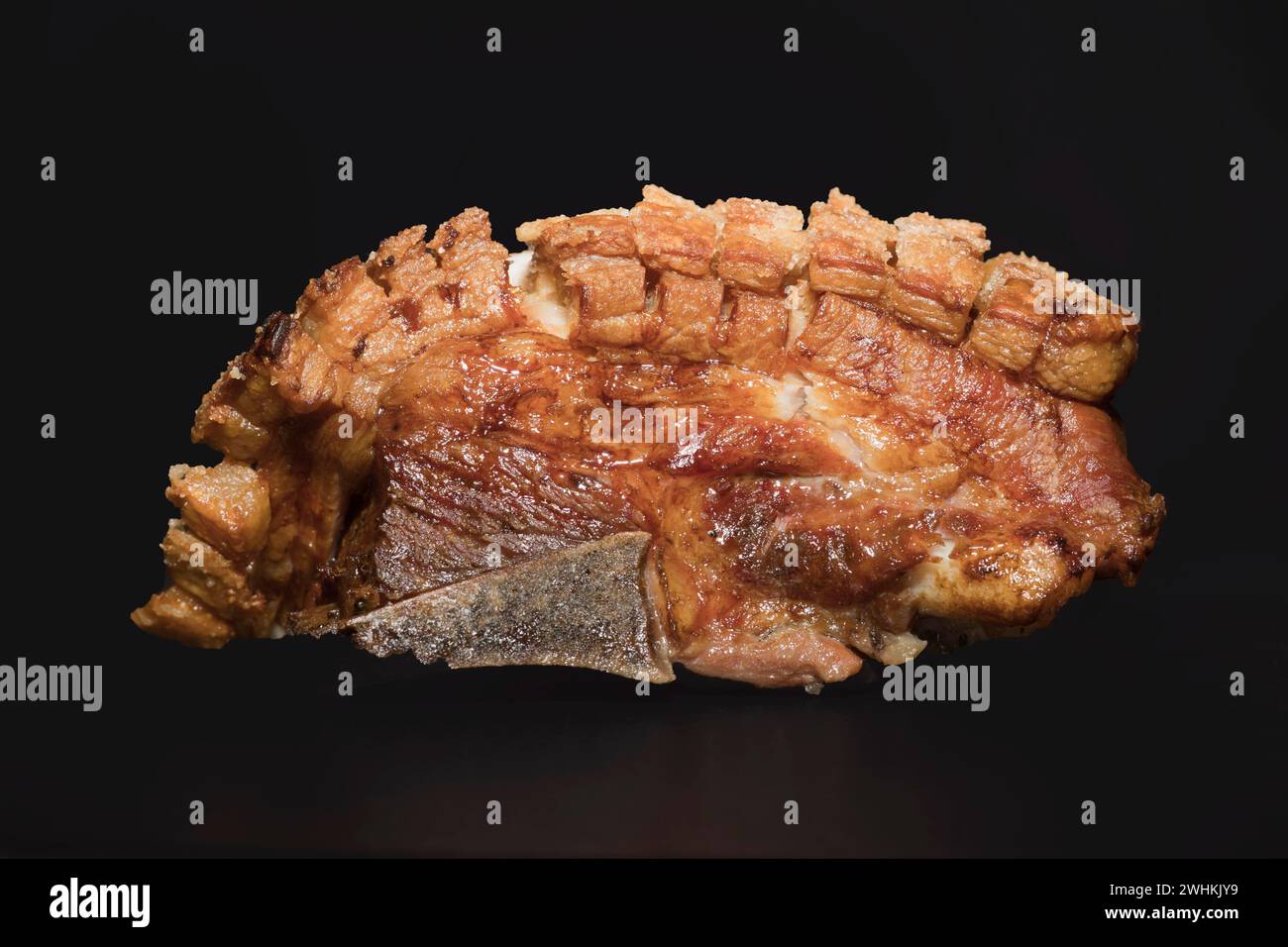 Freshly roasted pork belly with bone and crispy crust, food photography with black background Stock Photo