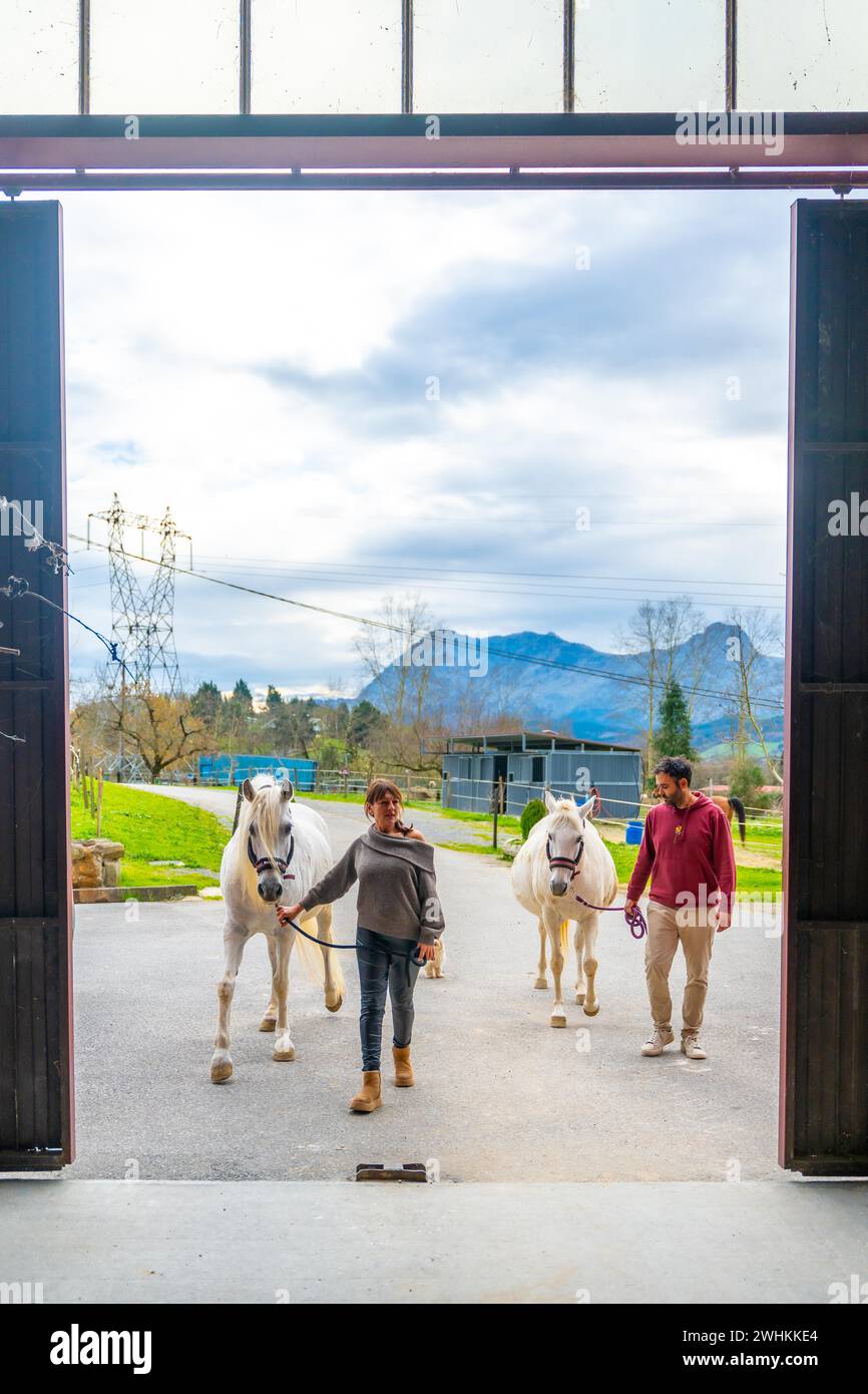 Vertical photo through a door of a stable of people walking carrying ...