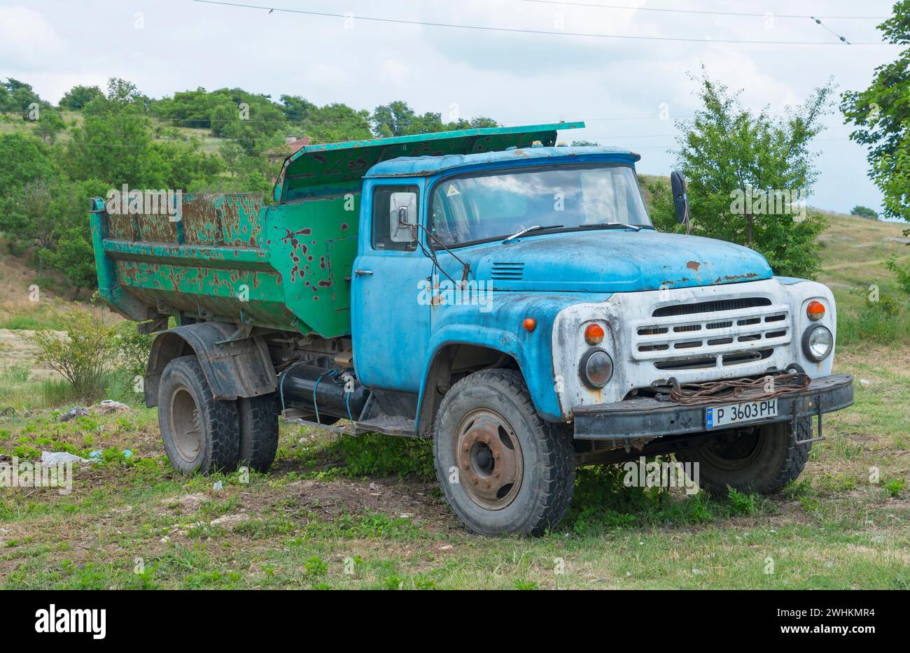Weathered blue lorry on a rural meadow under a cloudy sky, ZIL-130, Soviet Russian vehicle manufacturer Savod imeni Likhachova, Basarbovo, Basarbovo Stock Photo