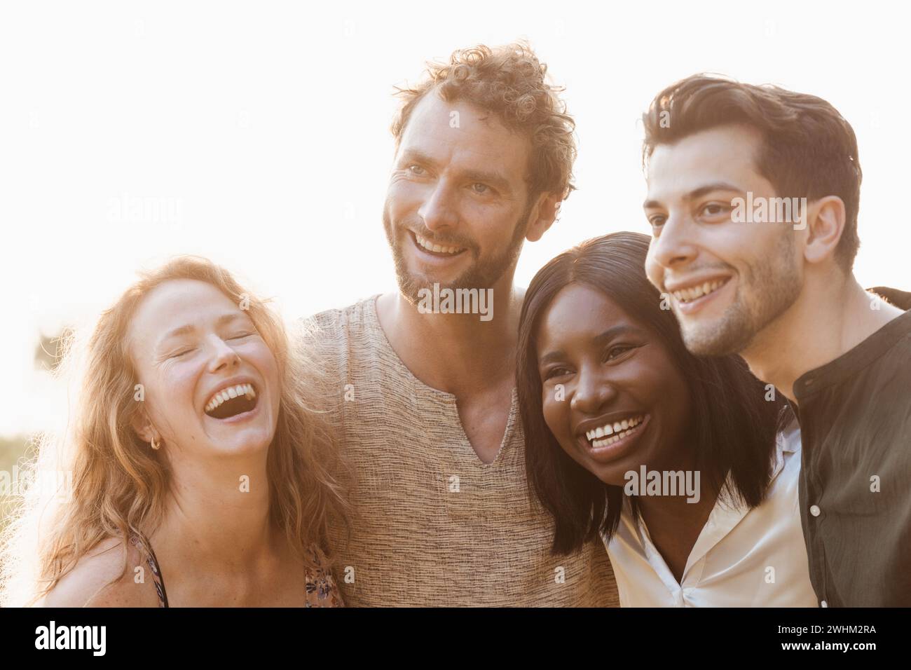 Group of young diverse people enjoy free time in summer, meet up in the park and have fun all together. Bunch of four happy exci Stock Photo