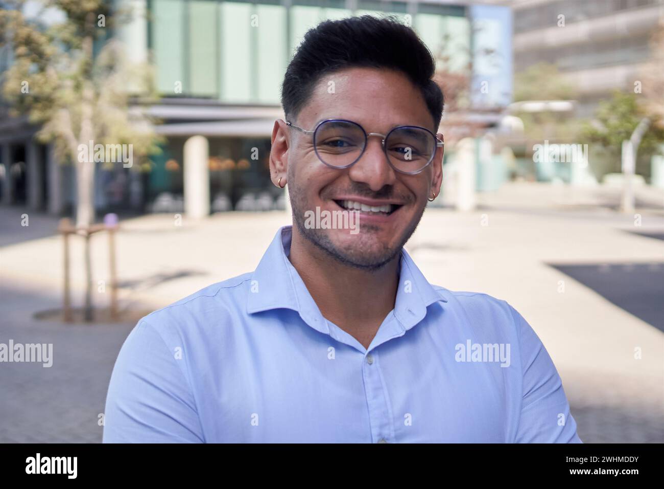 Portrait young adult Latin business man or commercial outside office center looking happy at camera. Stock Photo