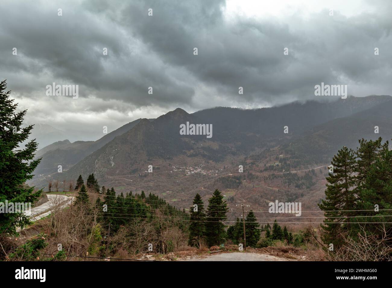 Dark clouds over Pindus mountains and firs trees as seen from the traditional village of Elati, near Trikala town, in Thessaly region, Central Greece, Stock Photo