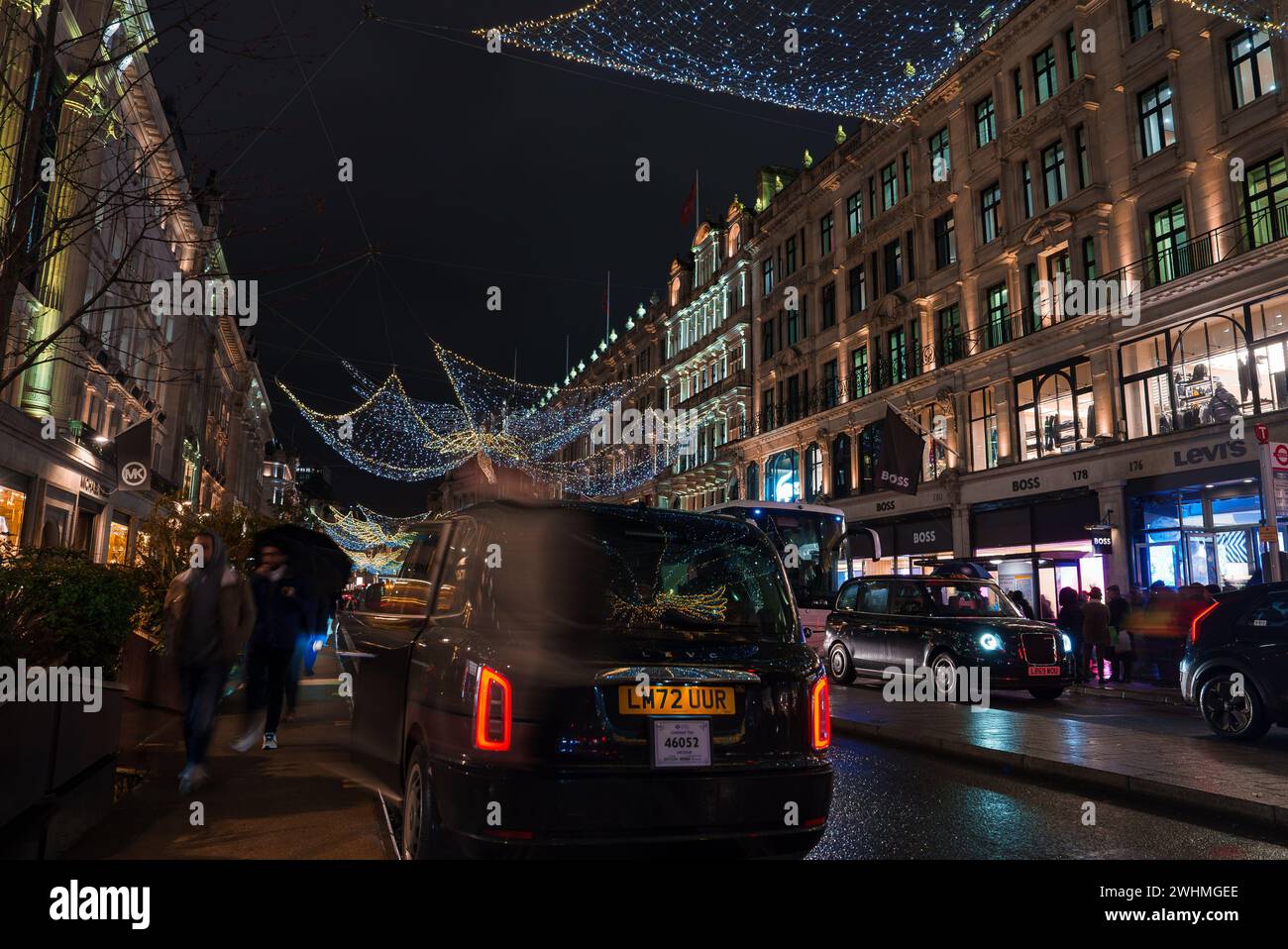 Christmas Lights Glow, Taxi Passes on a Lively London Street Scene. Stock Photo