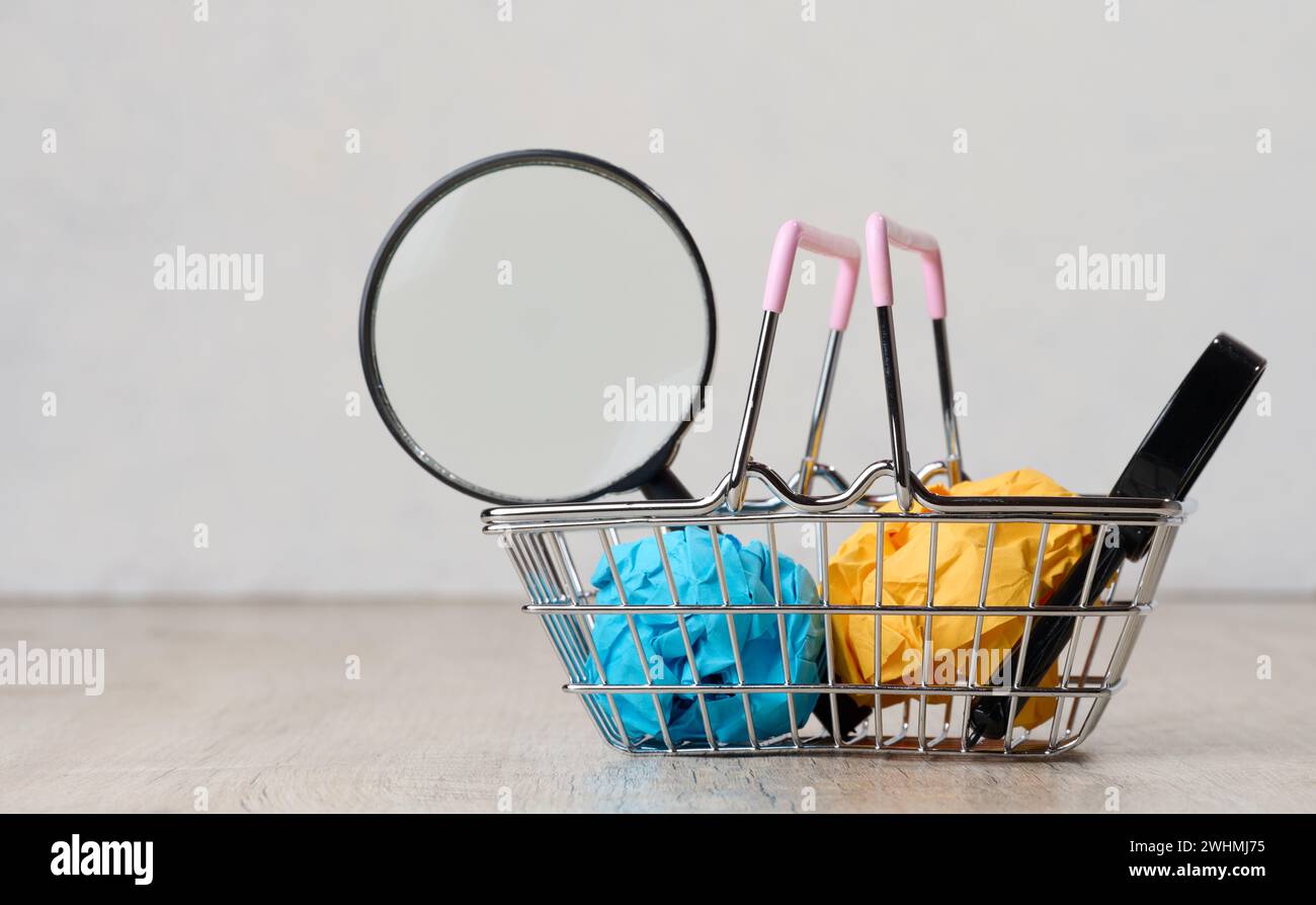 Miniature shopping basket and magnifying glass. Purchasing power concept Stock Photo