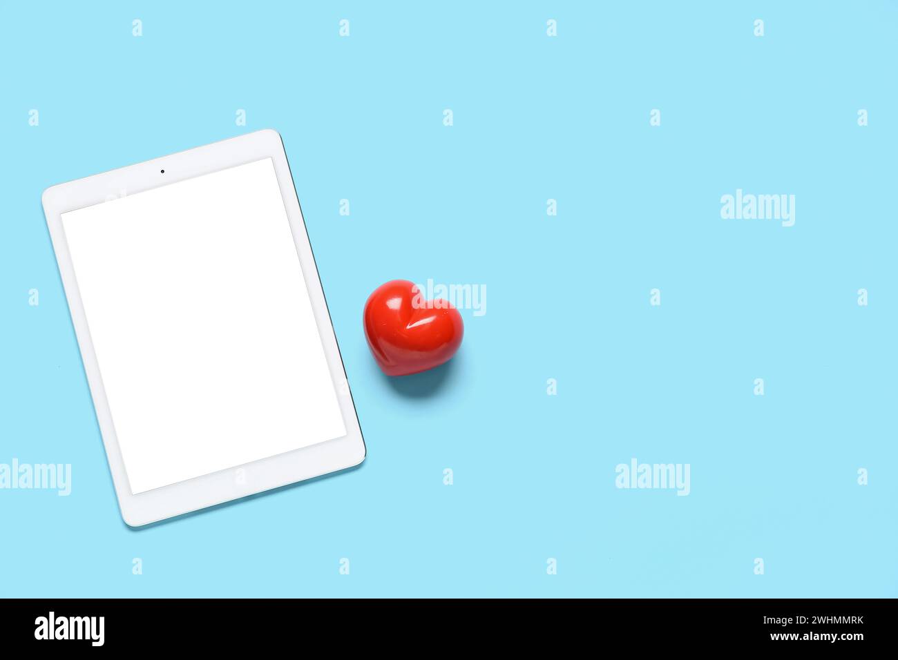Tablet computer with red heart on blue background. Concept of online dating Stock Photo