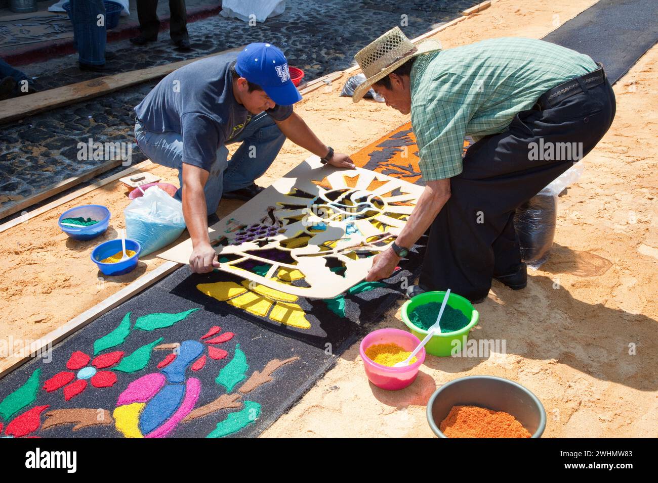 Antigua, Guatemala. Removing the stencil after making an alfombra (carpet) of colored sawdust to decorate the street in advance of the passage of a pr Stock Photo