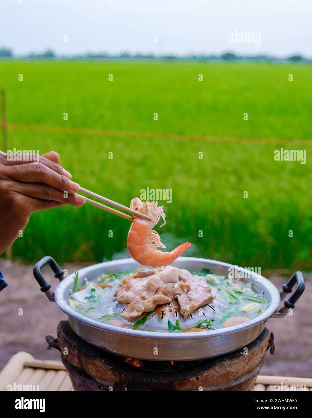 Thai korean bbq with a look over green rice fields at an homestay at a farm in Thailand Stock Photo