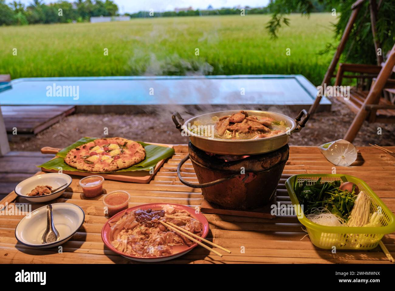 Thai korean bbq with a look over green rice fields at an homestay at a farm in Thailand Stock Photo