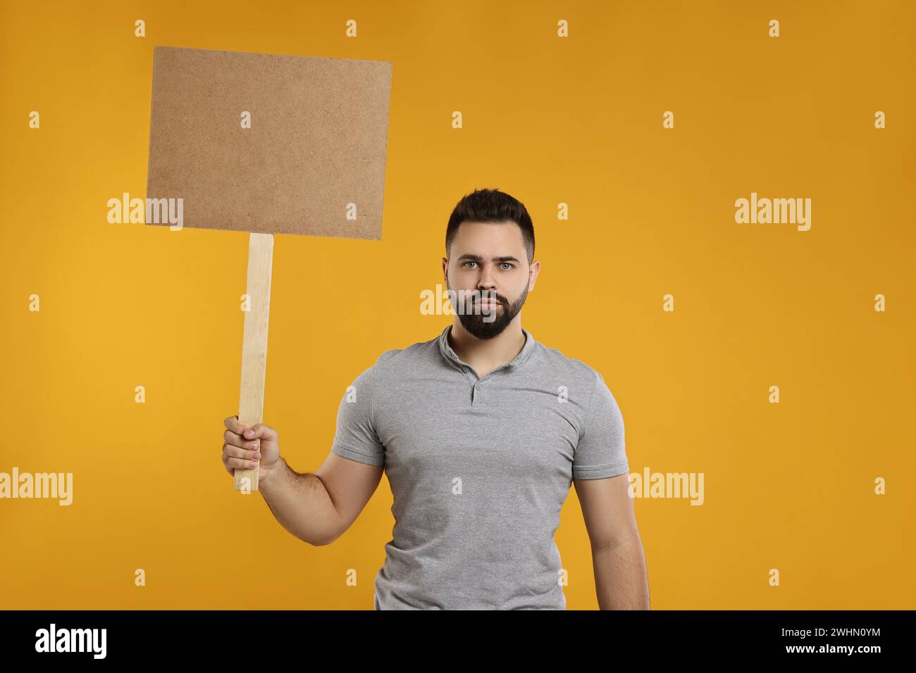 Upset man holding blank sign on orange background, space for text Stock Photo