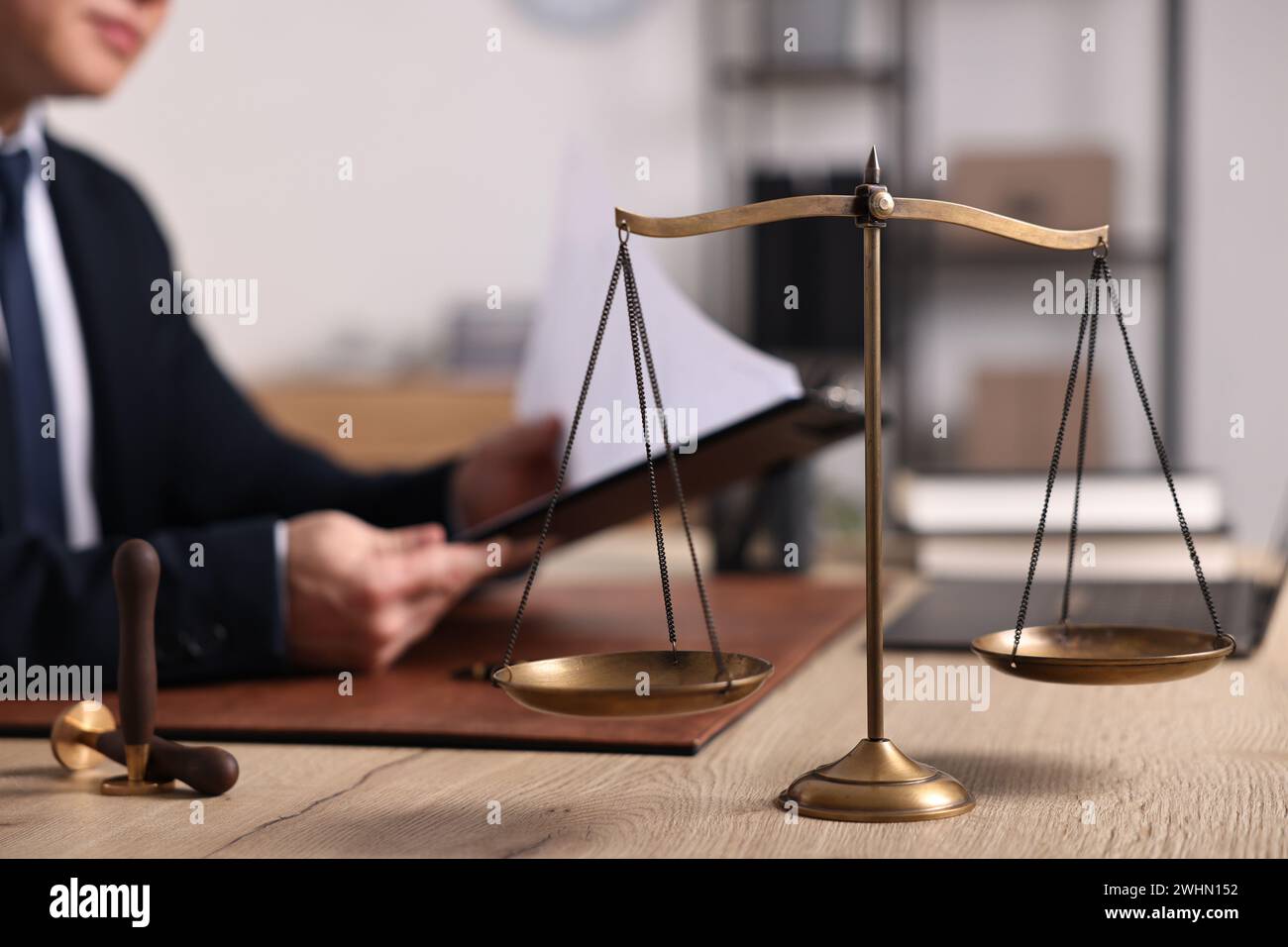 Notary working at wooden table in office, focus on scales of justice ...