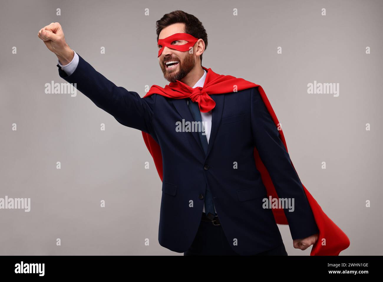 Happy businessman wearing red superhero cape and mask on beige ...