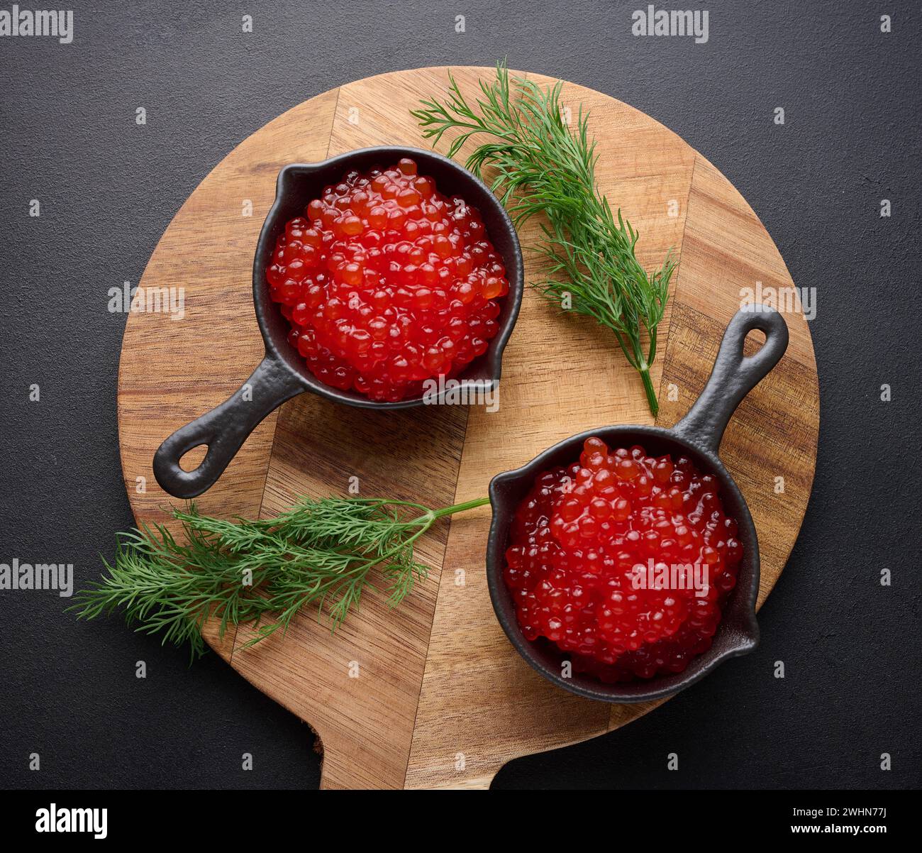 Red caviar in a black mini frying pan on the table, top view Stock Photo