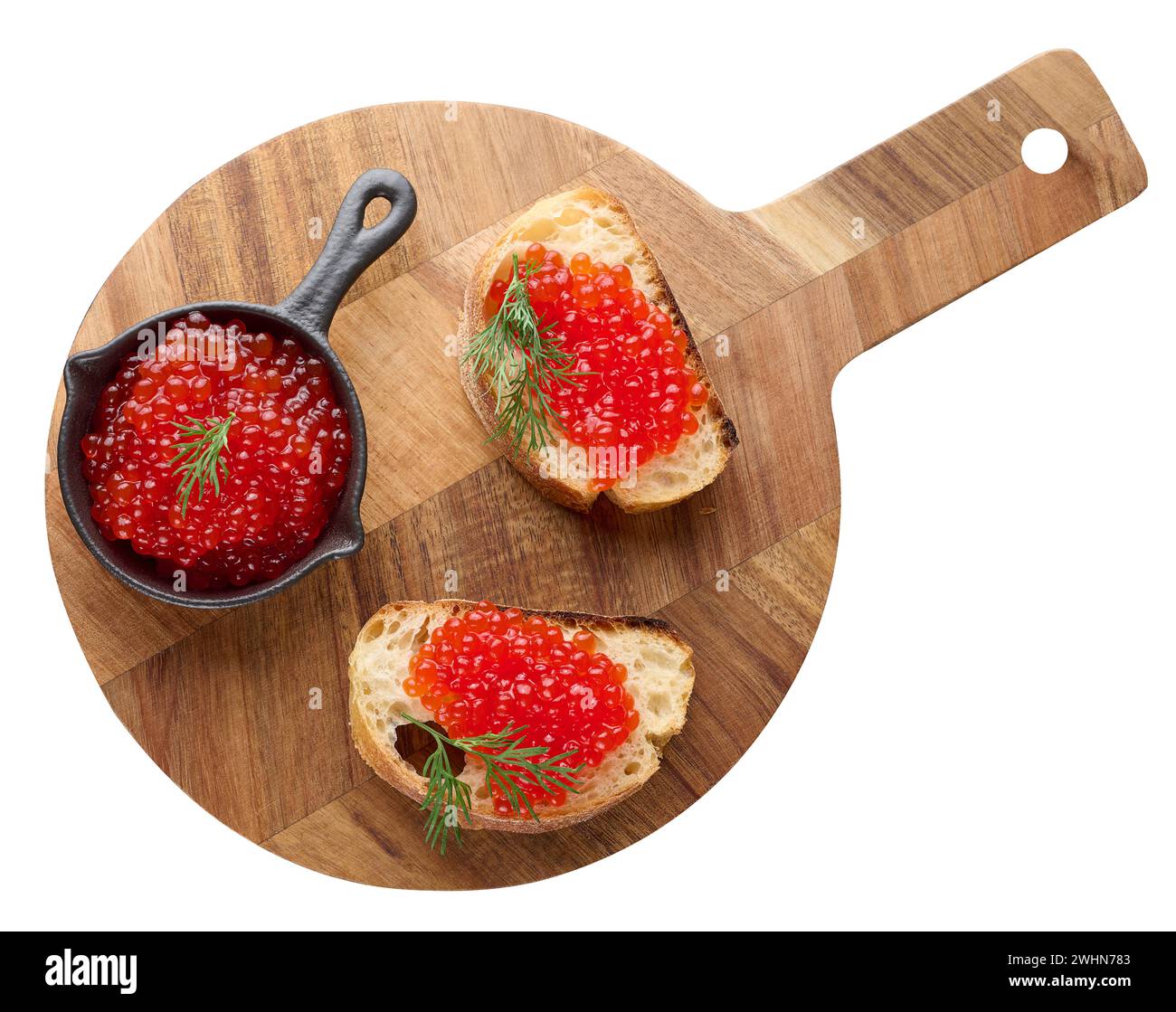 Red caviar in a black mini frying pan on a round wooden board, top view, concept of luxury and gourmet cuisine Stock Photo