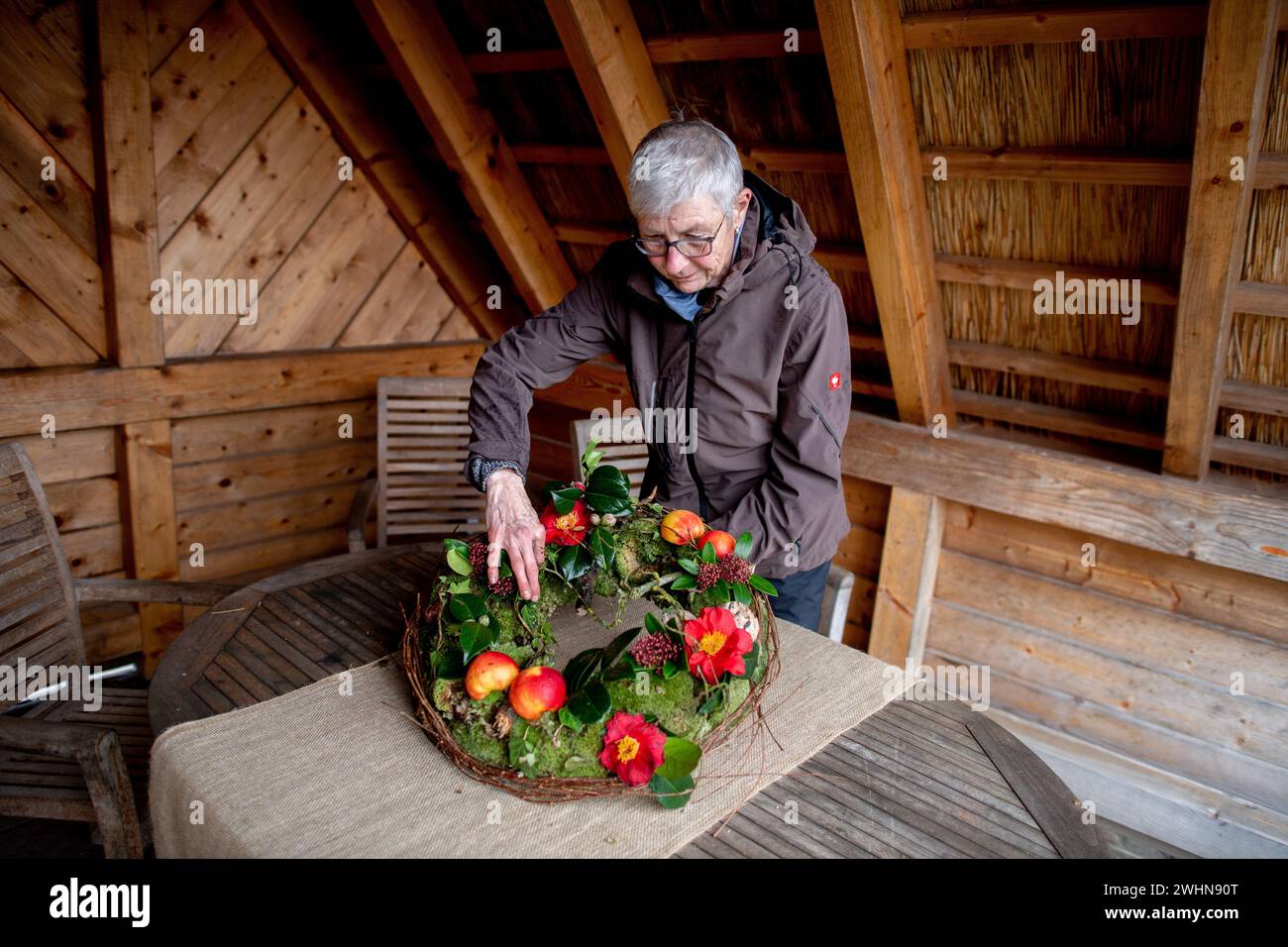 Bad Zwischenahn, Germany. 09th Feb, 2024. Florist Renate Klefer decorates a moss wreath with bird food in the Park der Gärten. As in many places in Lower Saxony, the gardening season in the Park der Gärten does not start until April - but a special opening for the 'Winter Blossom in the Park' attracts garden lovers to the park as early as February. Credit: Hauke-Christian Dittrich/dpa/Alamy Live News Stock Photo