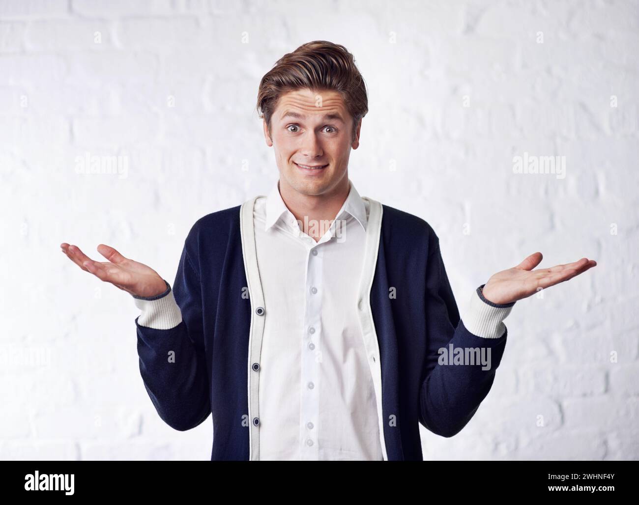 Confused, shrug and portrait of man with doubt on wall background for choice, option and decision. Facial expression, thinking and isolated person Stock Photo