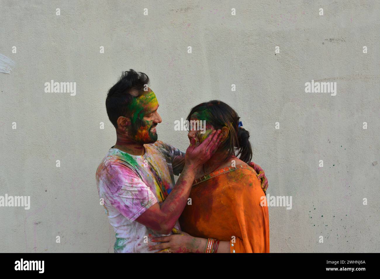 Portrait of a young Indian boy and girl playing holi. Happy couple enjoying in holi festival. Portrait of Indian couple covered in holi colors. Happy Stock Photo
