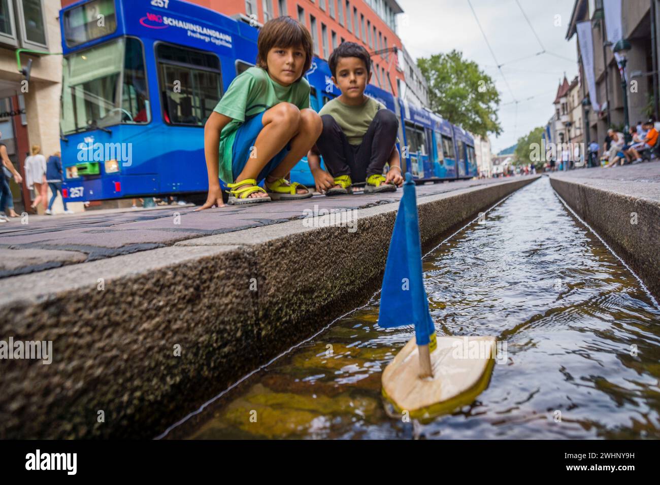 NiÃ±os jugando con un barquito de madera en los canales de agua Stock Photo