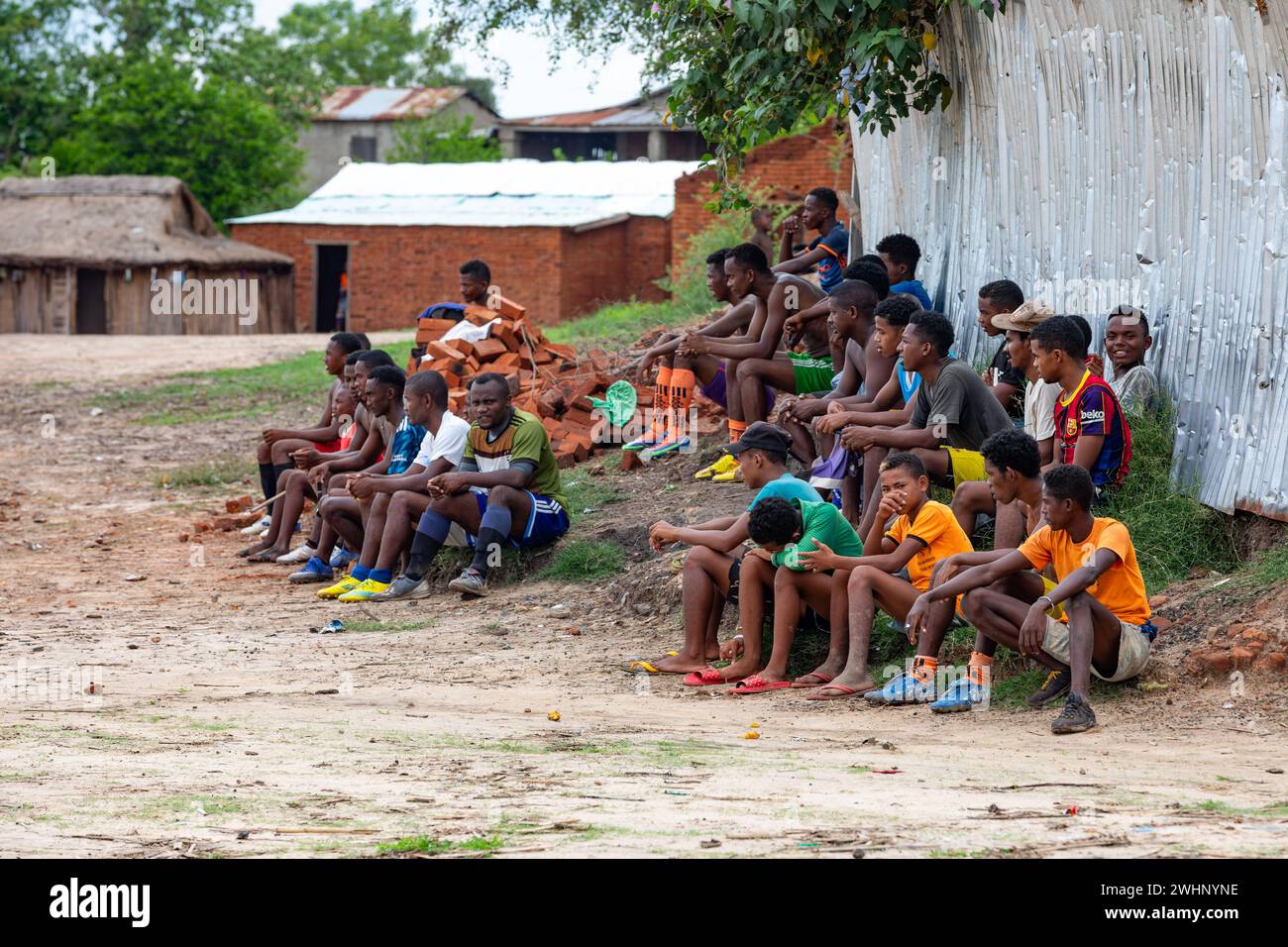 Soccer fans sitting on the ground and watching a local match between two teams from the village. Bekopaka Madagascar Stock Photo