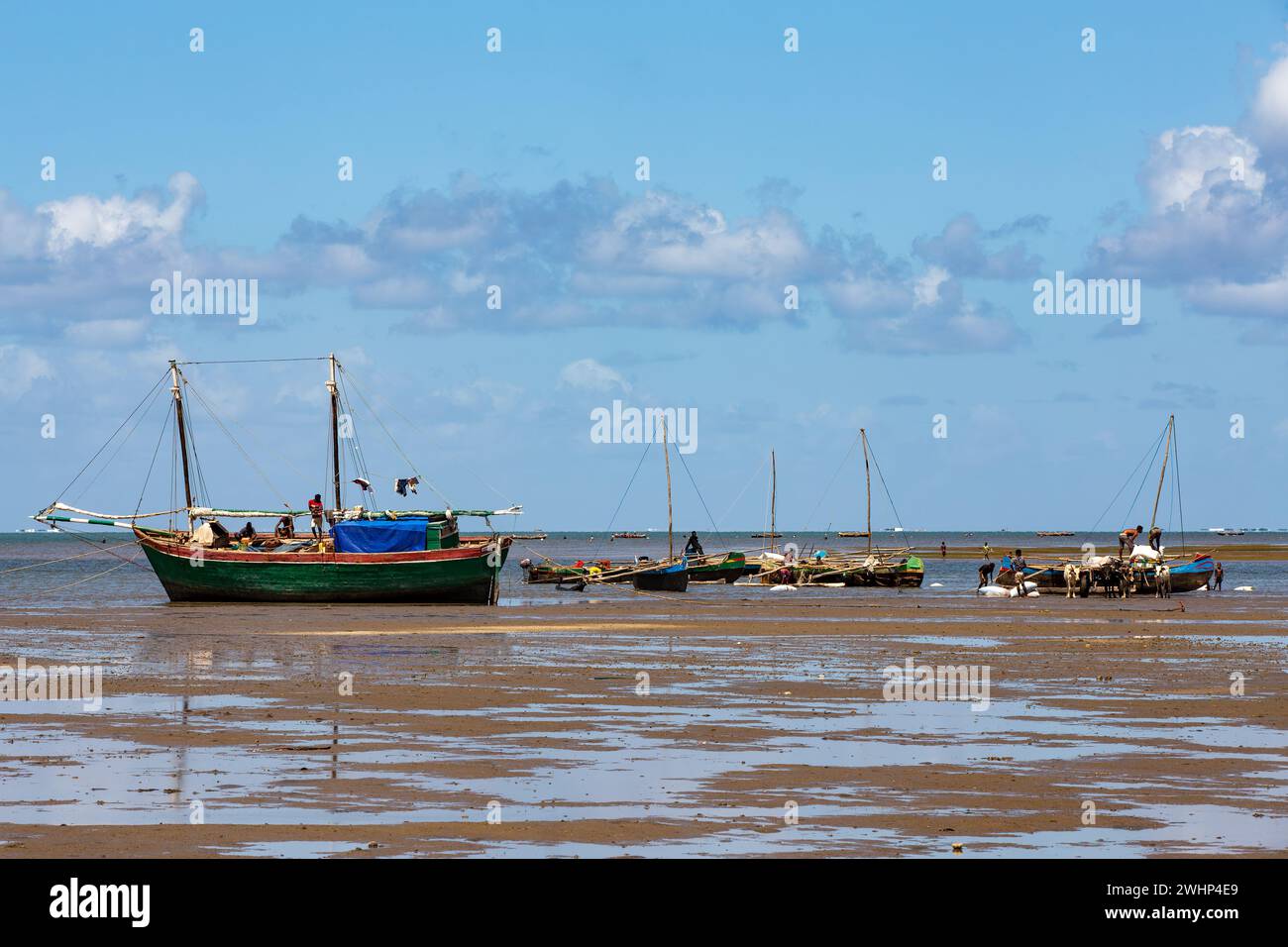 Fishing boat stranded on the dry port during low tide with Malagasy people around. Stock Photo