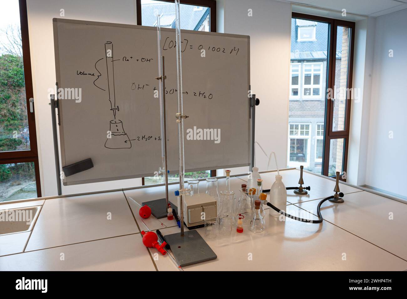 Titration setup in a chemistry classroom at school with on a whiteboard a drawing and some chemistry formulas for the experiment. Stock Photo