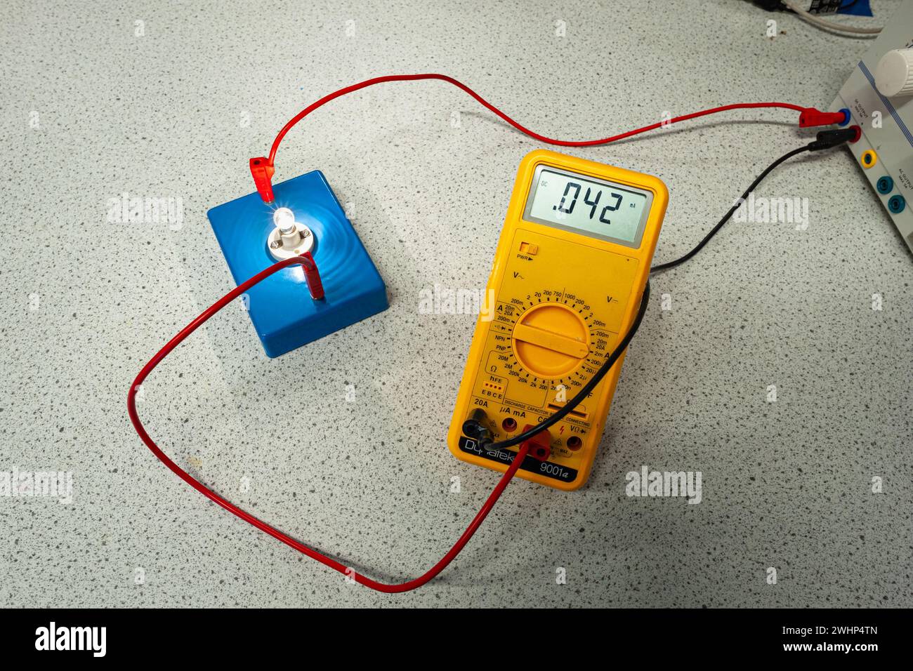 Measuring the electrical current with a multimeter through a lit light bulb. Stock Photo