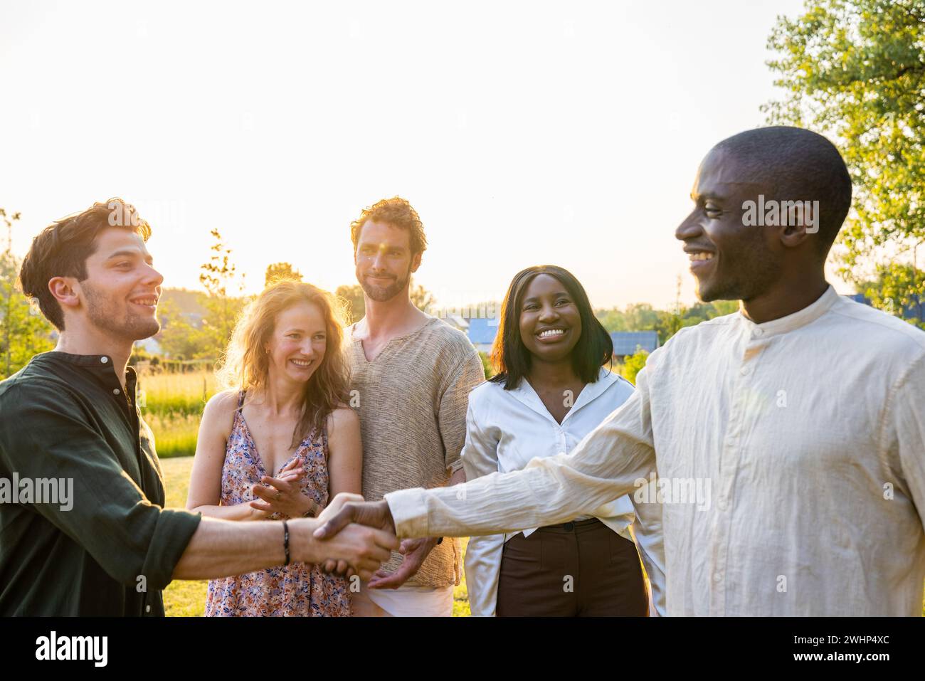 Virtual Victory Handshake: Multi-Ethnic Fun at Garden Party Stock Photo