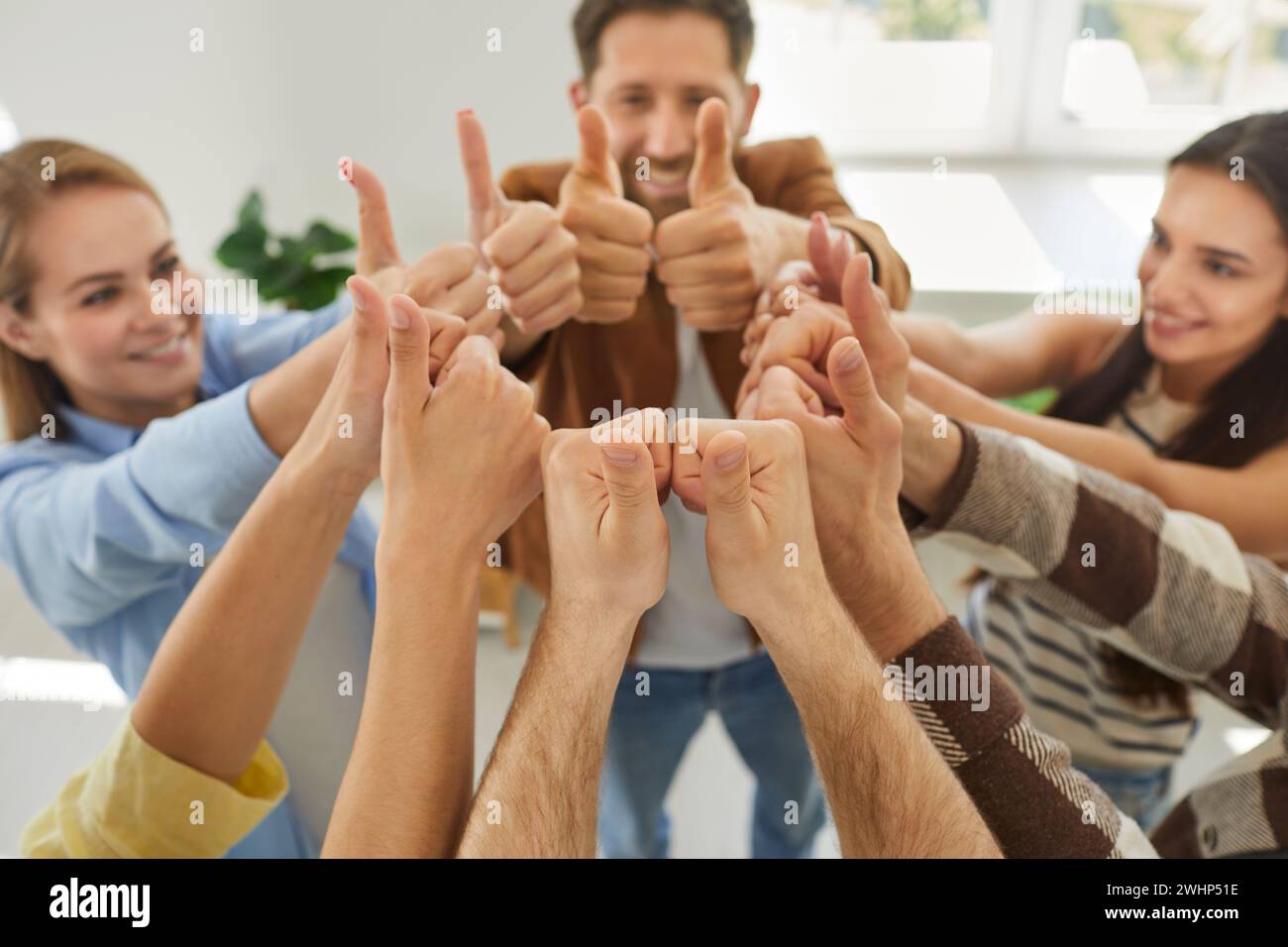Happy smiling people friends putting their arms together in a circle showing thumb up sign. Stock Photo