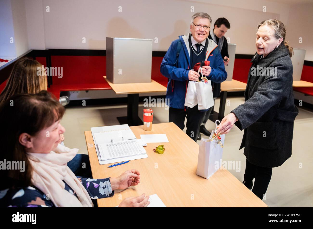 Berlin, Germany. 11th Feb, 2024. Ruth Brand (r-l), Federal Returning Officer, and Stephan Bröchler, State Returning Officer for Berlin, visit the polling station at the Carl-von-Ossietzky-Gymnasium in Berlin-Pankow and hand out gift bags to the election workers. Due to numerous glitches, the 2021 Bundestag election in Berlin will have to be partially repeated. This was decided by the Federal Constitutional Court on December 19, 2023. Credit: Christoph Soeder/dpa/Alamy Live News Stock Photo