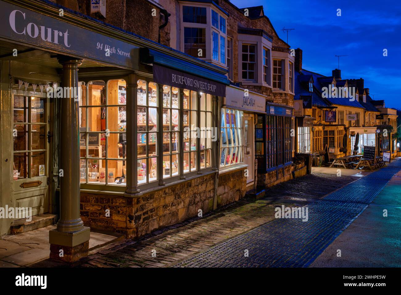 Shops along the high street in Burford at dawn. Cotswolds, Oxfordshire, England Stock Photo