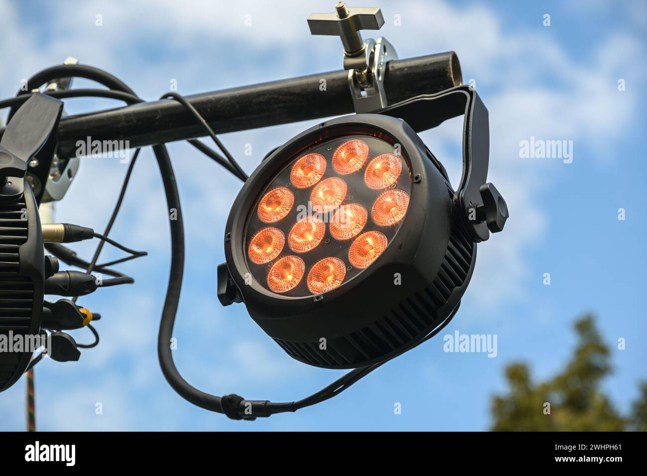 LED floodlight with RGB colors as outdoor stage lightning, installed on a black steel beam against the blue sky, used for festiv Stock Photo