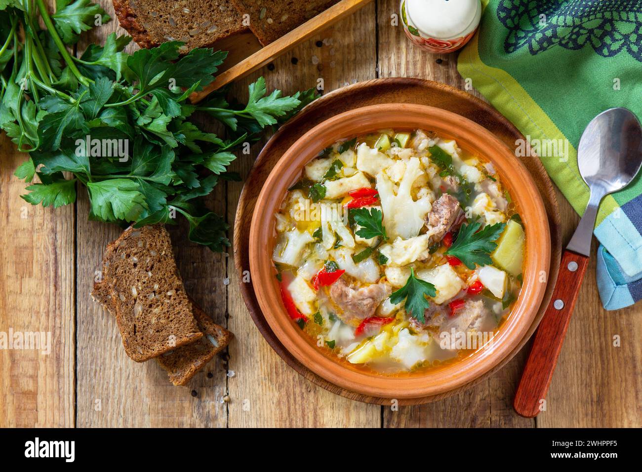 Traditional Hungarian thick soup with beef, vegetables and dumplings on a wooden table. Hot dinner or lunch. Flat lay, top view. Stock Photo