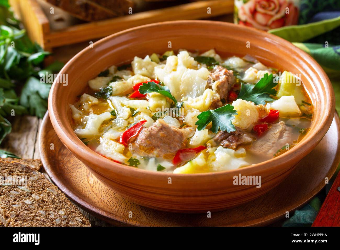 Traditional Hungarian thick soup with beef, vegetables and dumplings on a wooden table. Hot dinner or lunch. Stock Photo