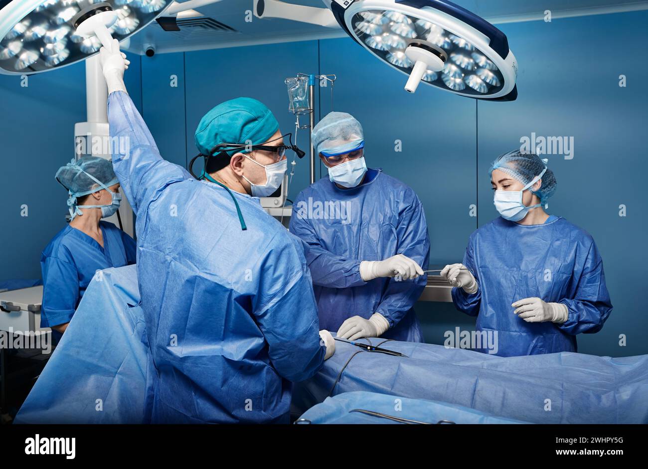 Group of concentrated surgeons while surgical operation in operating theater. Teamwork in surgical department Stock Photo