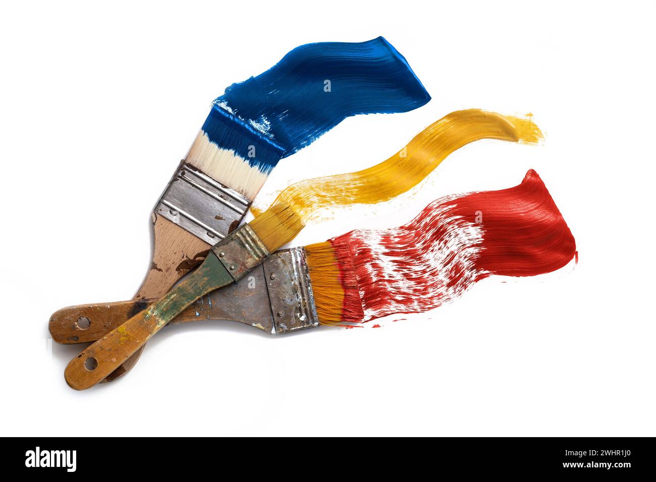 Various flat brushes painting blue, yellow and red color on a white
