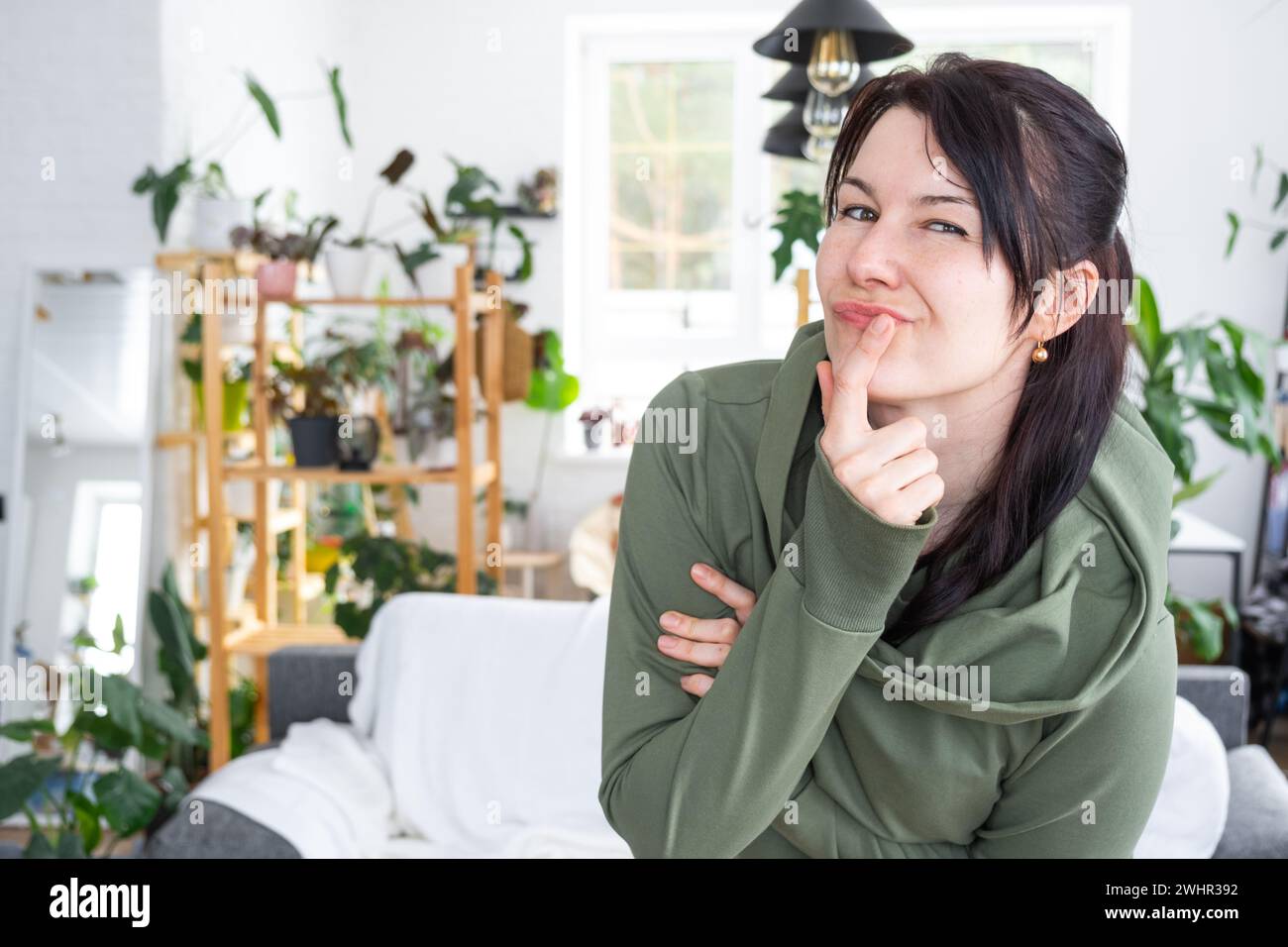 Thoughtful emotions of a woman in her home in a bright modern interior with home plants. Portrait of a dreamy Stock Photo