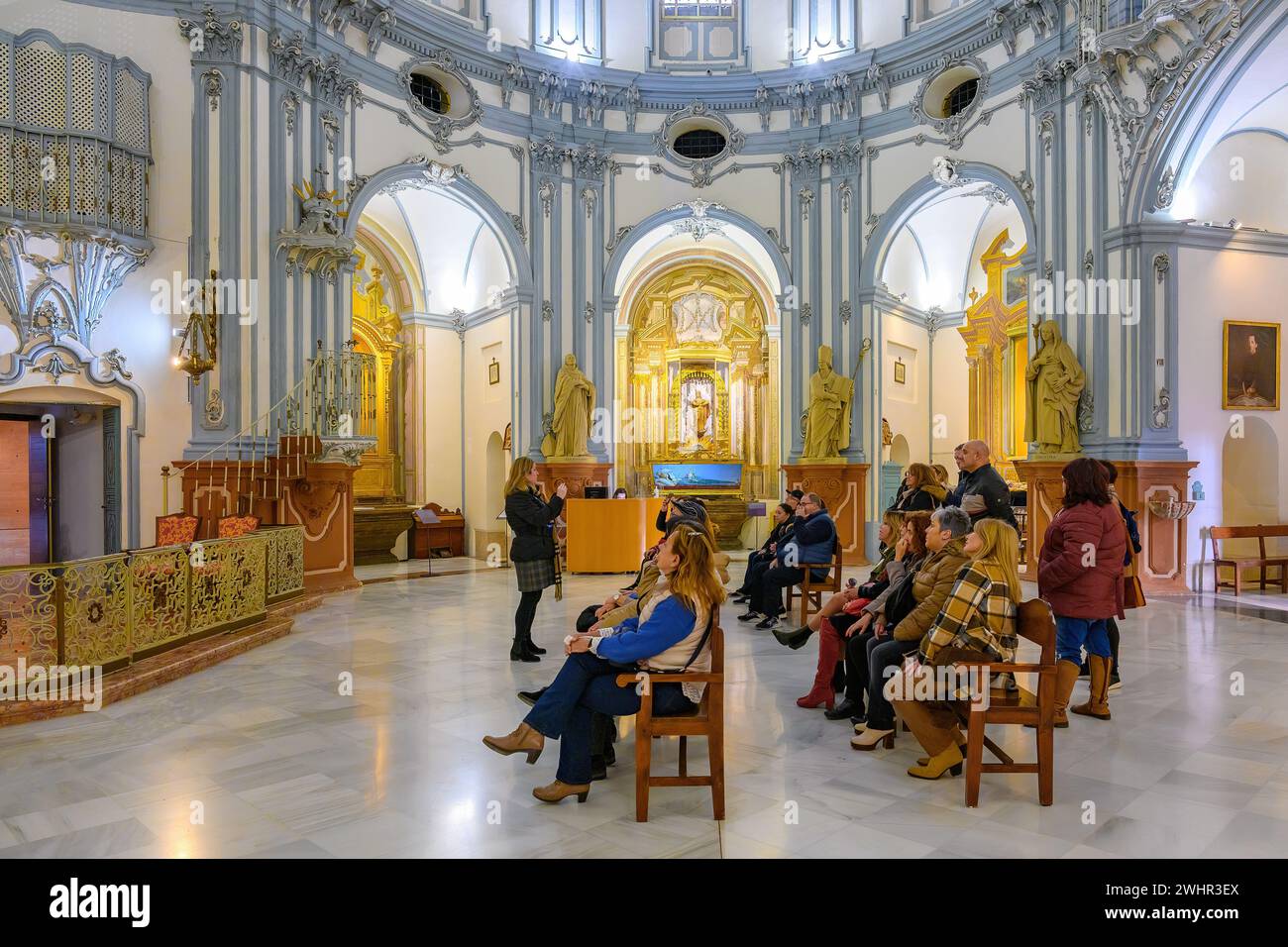 A group of tourists sitting in chairs and listening to a guide explanation. Interior architectural feature of the Museum Church Saint John of God Stock Photo
