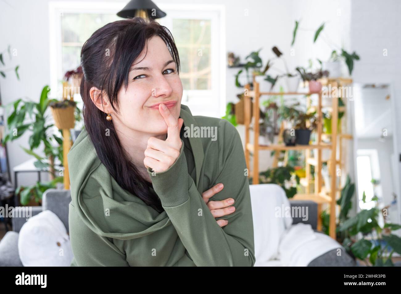Thoughtful emotions of a woman in her home in a bright modern interior with home plants. Portrait of a dreamy Stock Photo