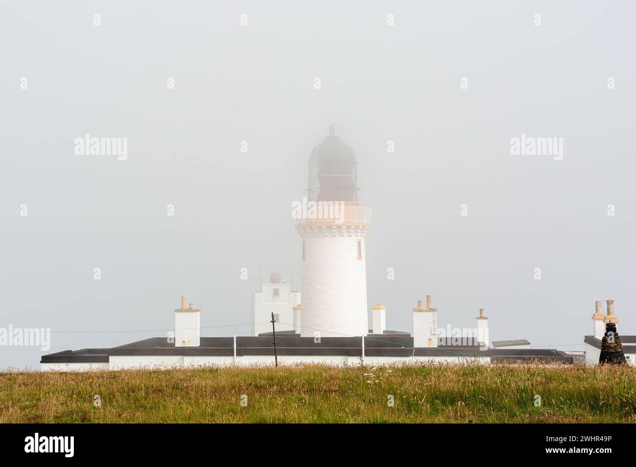 Dunnet Head Lighthouse covered with low clouds Stock Photo