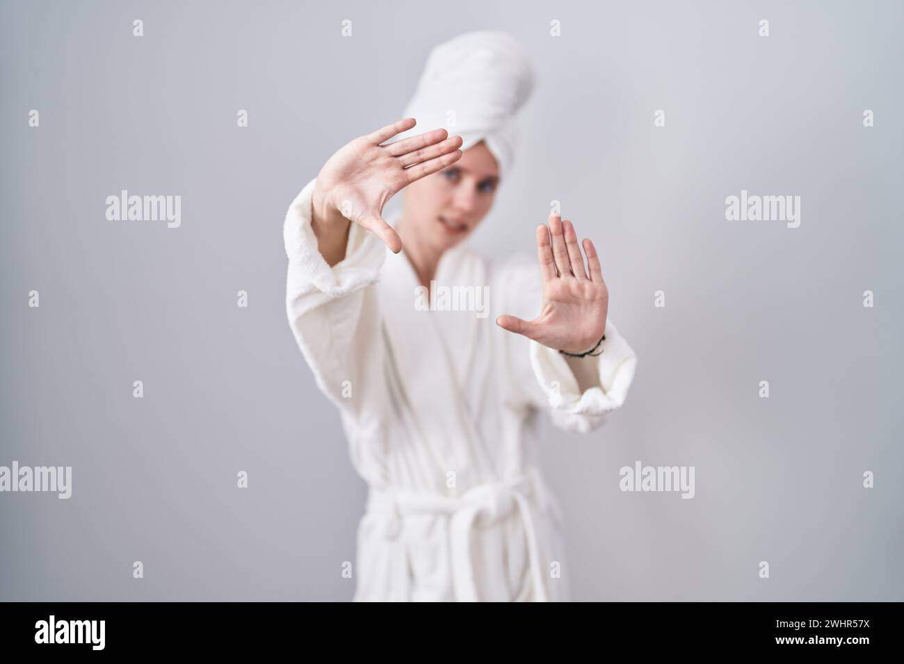 Blonde caucasian woman wearing bathrobe doing frame using hands palms ...
