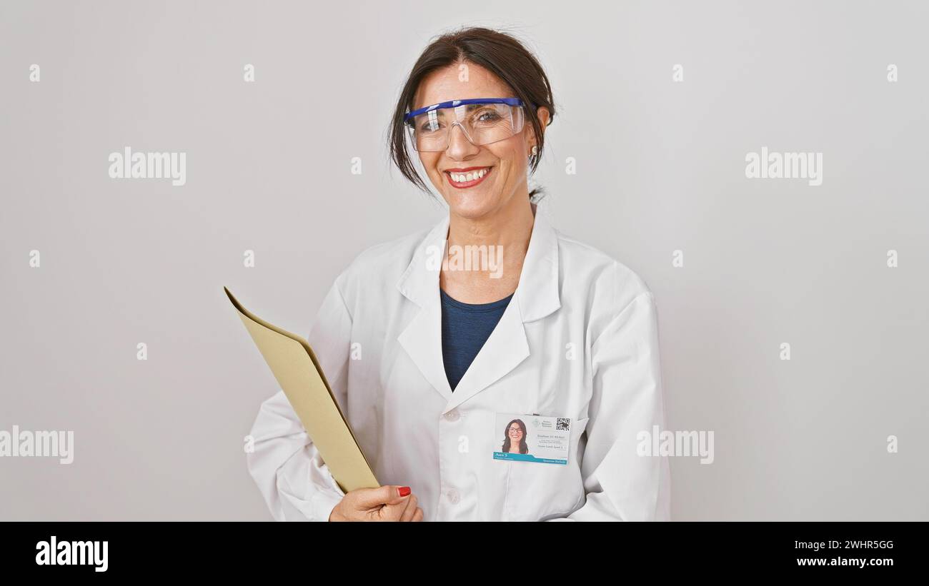 A smiling hispanic woman in safety glasses and a lab coat holding a ...