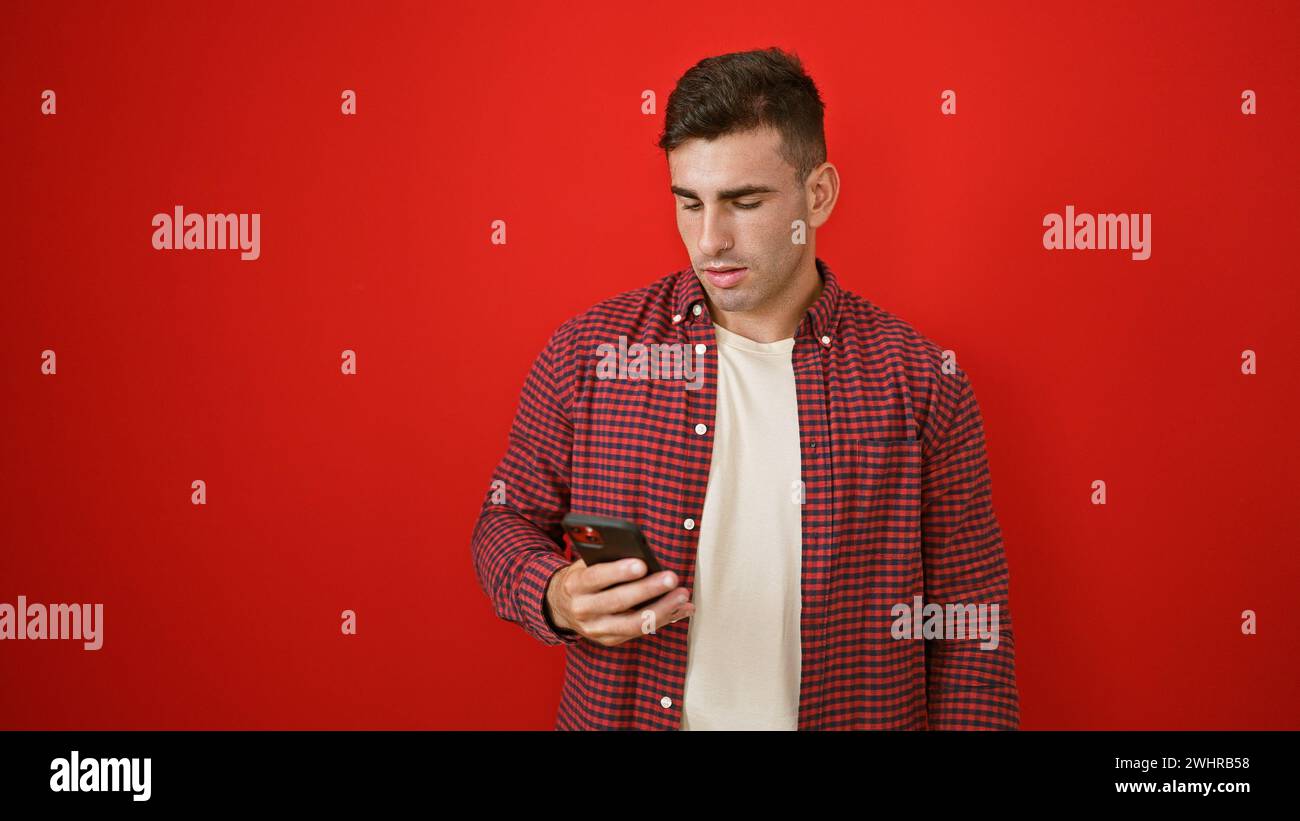 Young hispanic man using smartphone over isolated red background Stock Photo