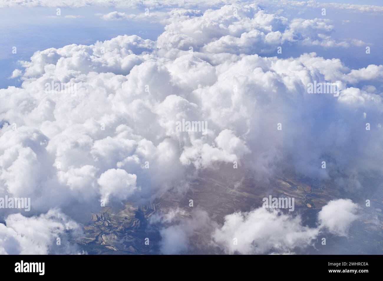 An aerial view showcasing cumulus clouds, blue sky, and a glimpse of ...