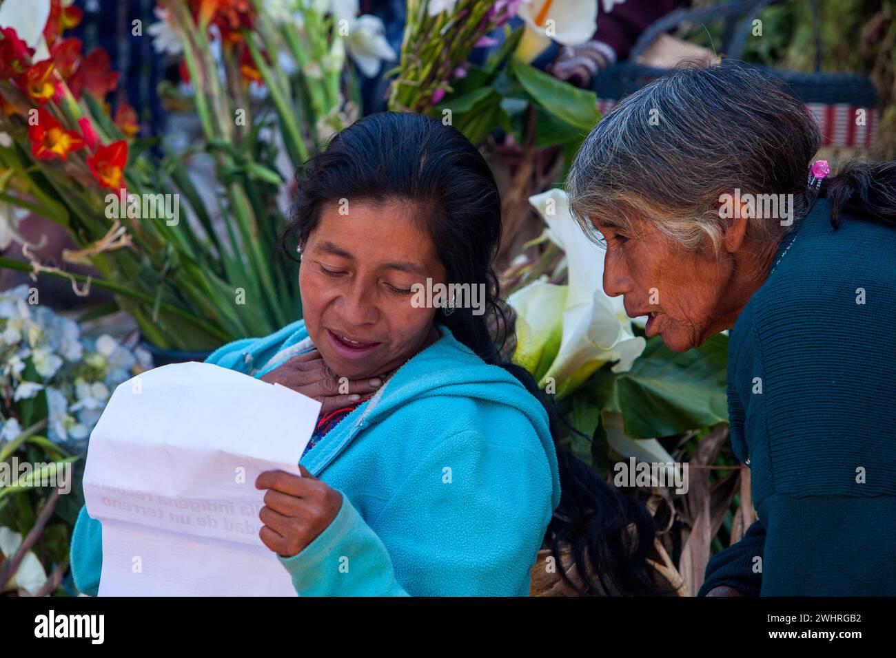Chichicastenango, Guatemala.  Two Quiche (Kiche, K'iche') Women Looking at an Article on Steps of Santo Thomas Church, Sunday Morning. Stock Photo
