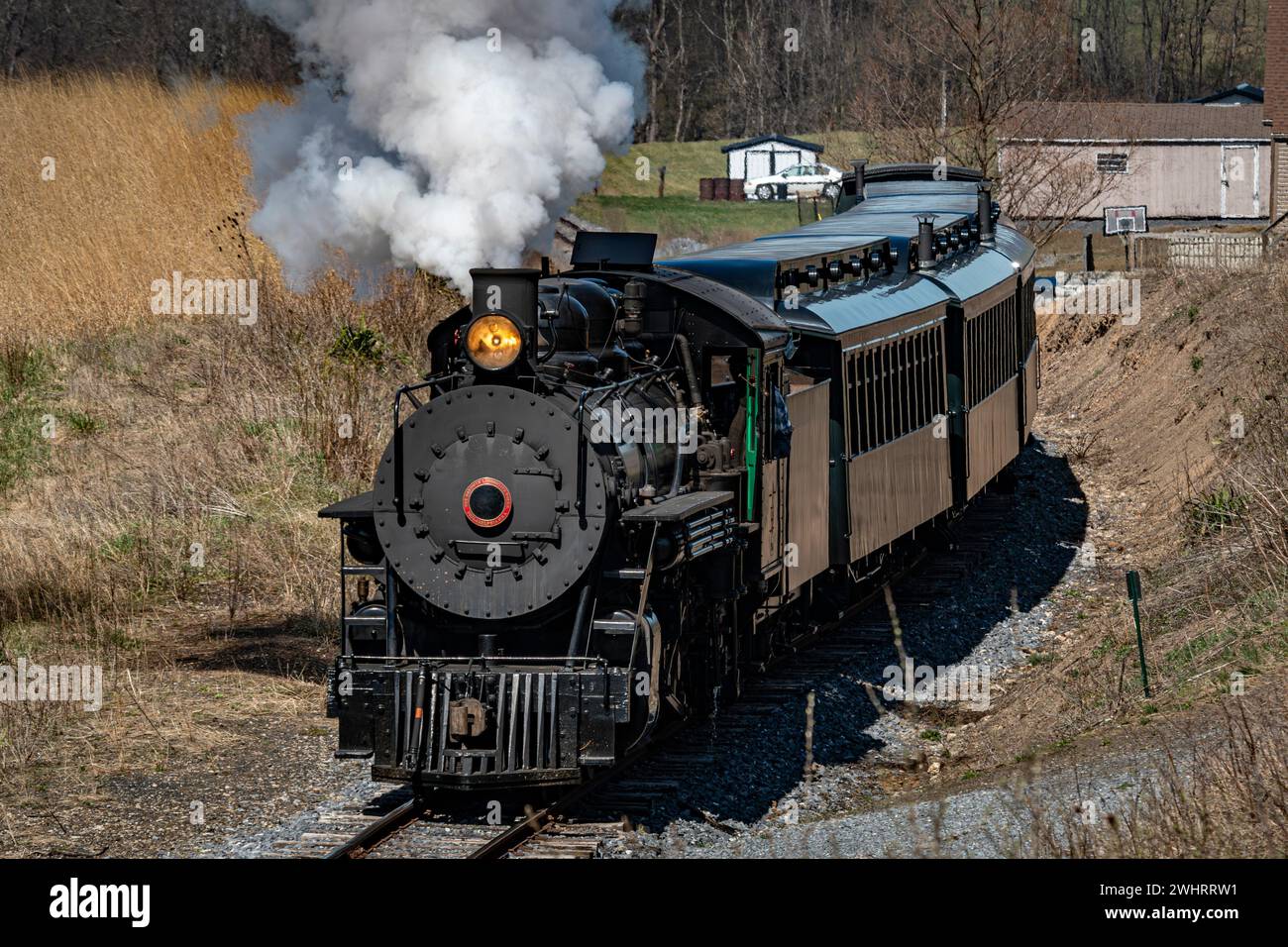 Front and Slightly Above View Approaching Restored Narrow Gauge Passenger Steam Train Blowing Smoke Stock Photo