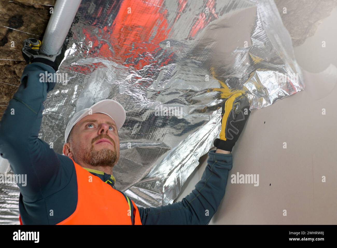 the construction worker holds a vapor barrier in his hand - preparation ...