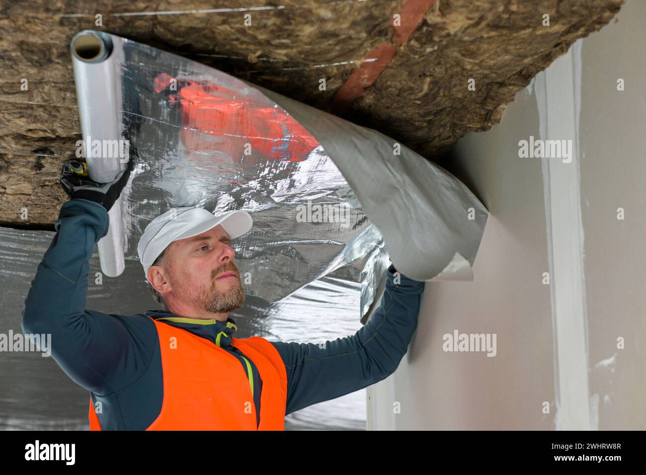 the construction worker holds a vapor barrier in his hand - preparation ...